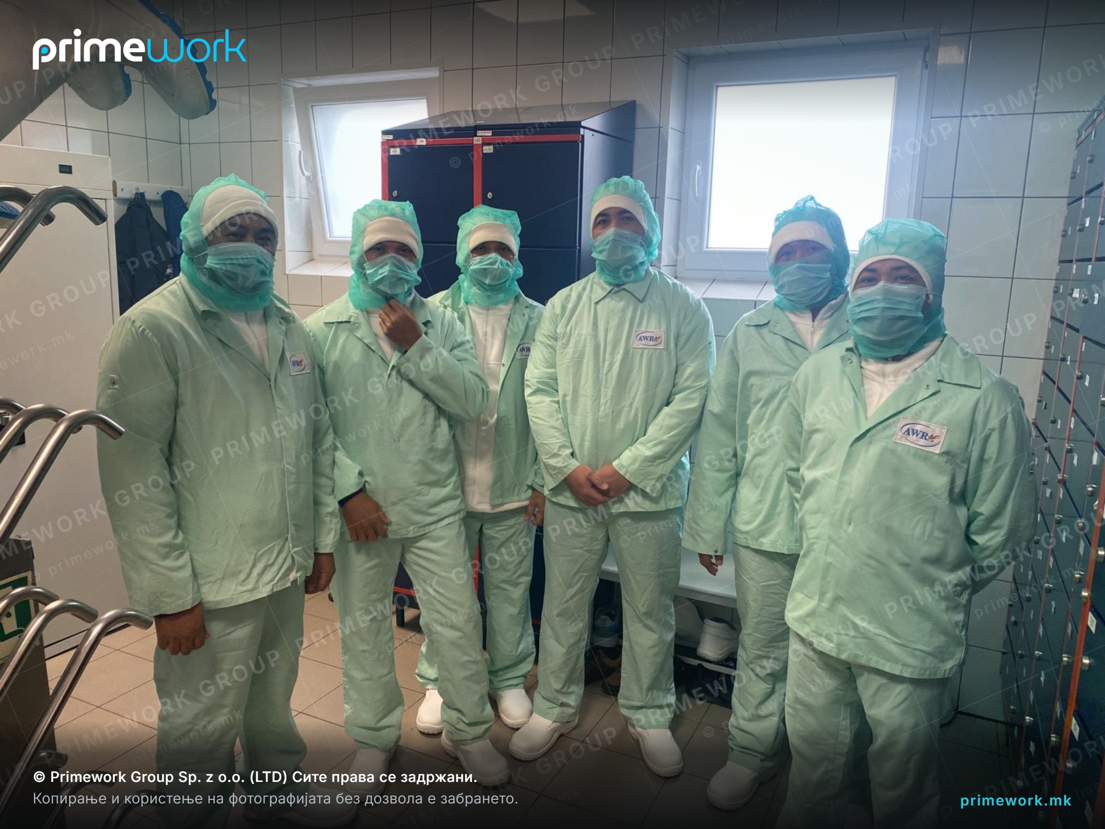 Workers from Asia in protective clothing and masks in the clean zone of a food plant