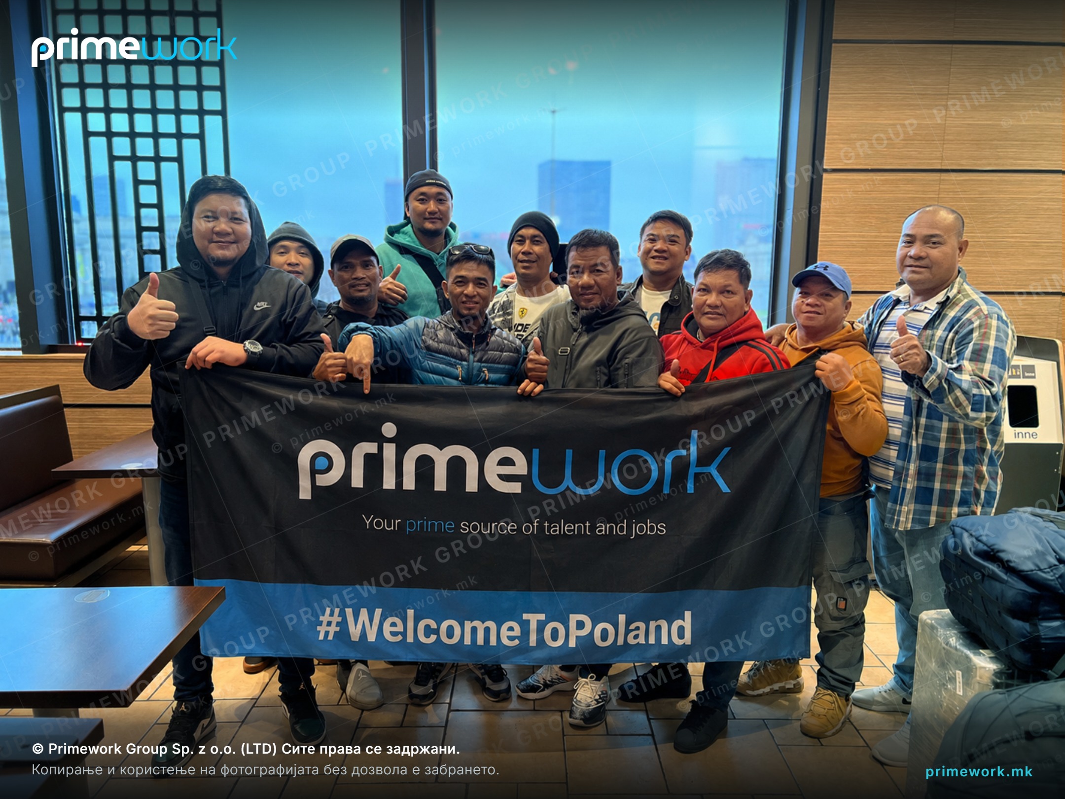 A group of workers from Asia holding a Primework Group banner on arrival day