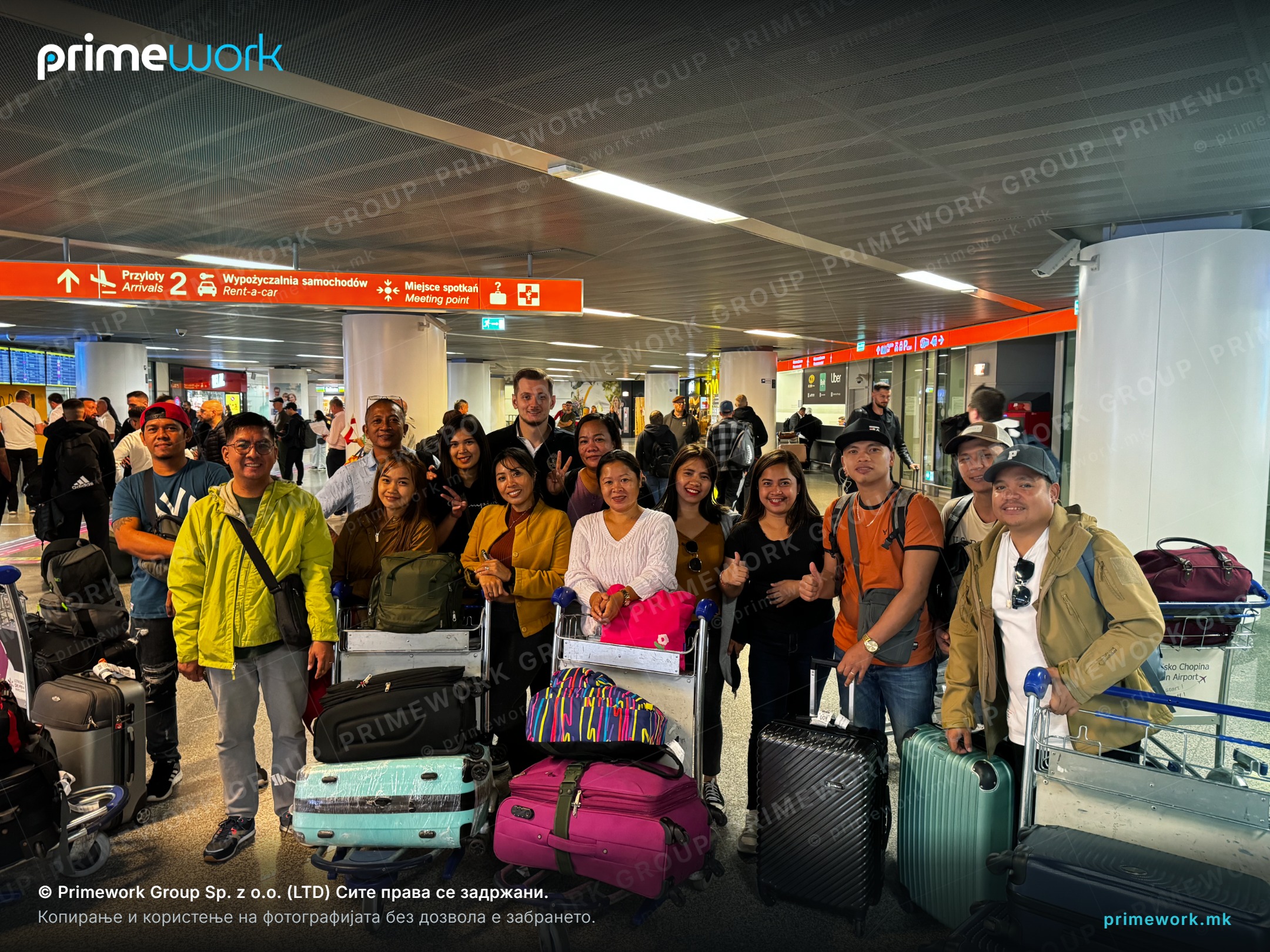A group of Filipino workers with luggage in an airport arrivals hall
